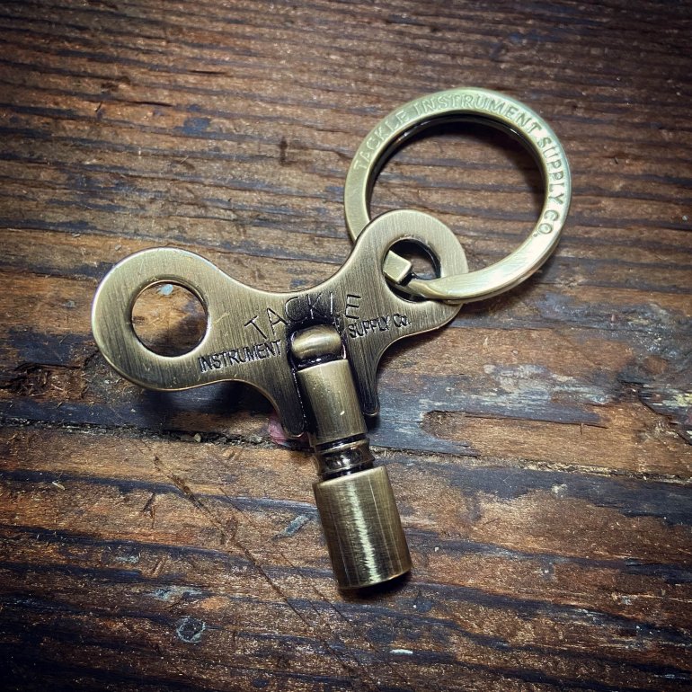 Timekeepers Drum Key fra Tackle vist i antique brass vist på et træbord uden etui