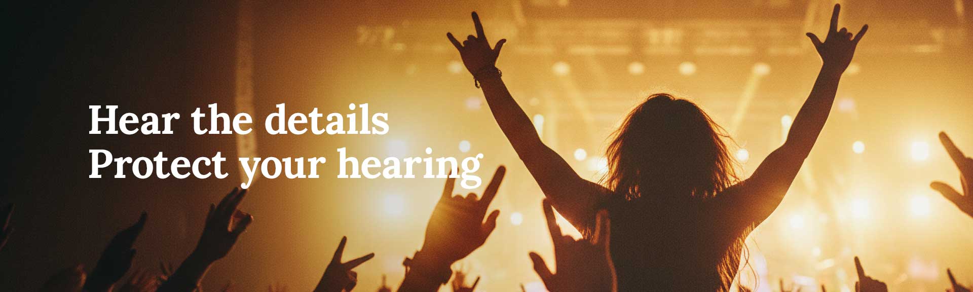 Concert crowd with hands in the air in front of a brightly lit stage