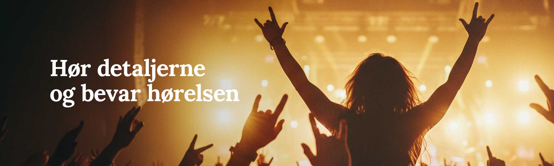 Publikum til live koncert med h&aelig;nder i vejret foran oplyst scene